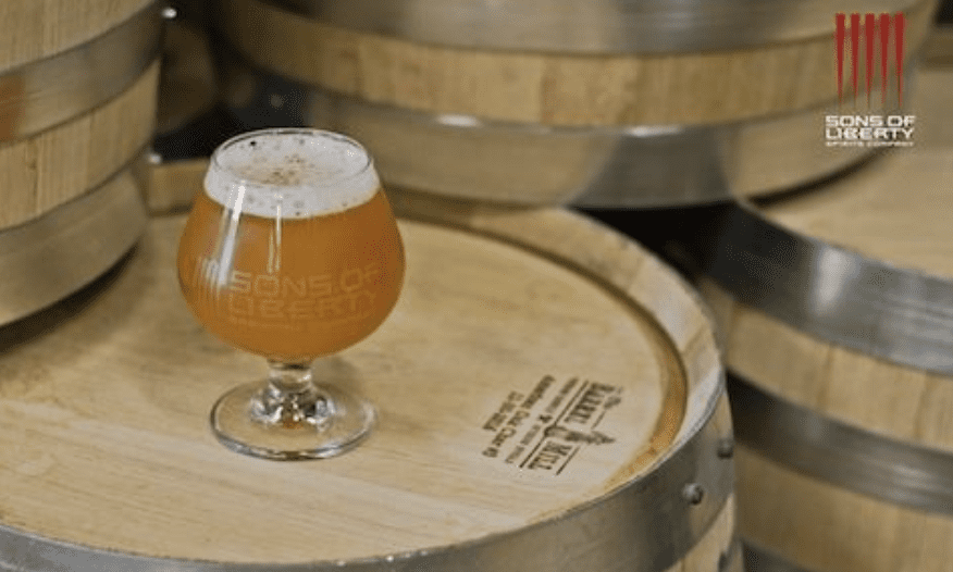 A glass of beer sitting on top of barrels.