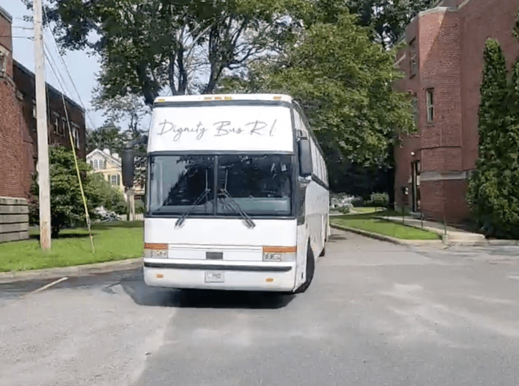 A white bus parked in front of a brick building.