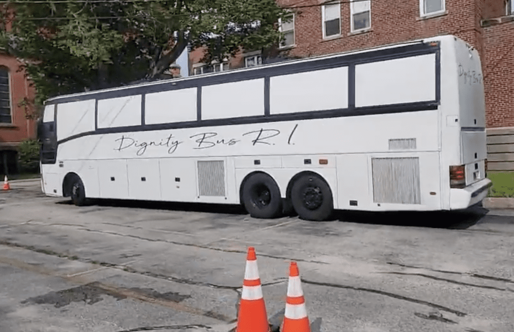 A white bus parked in front of a building.