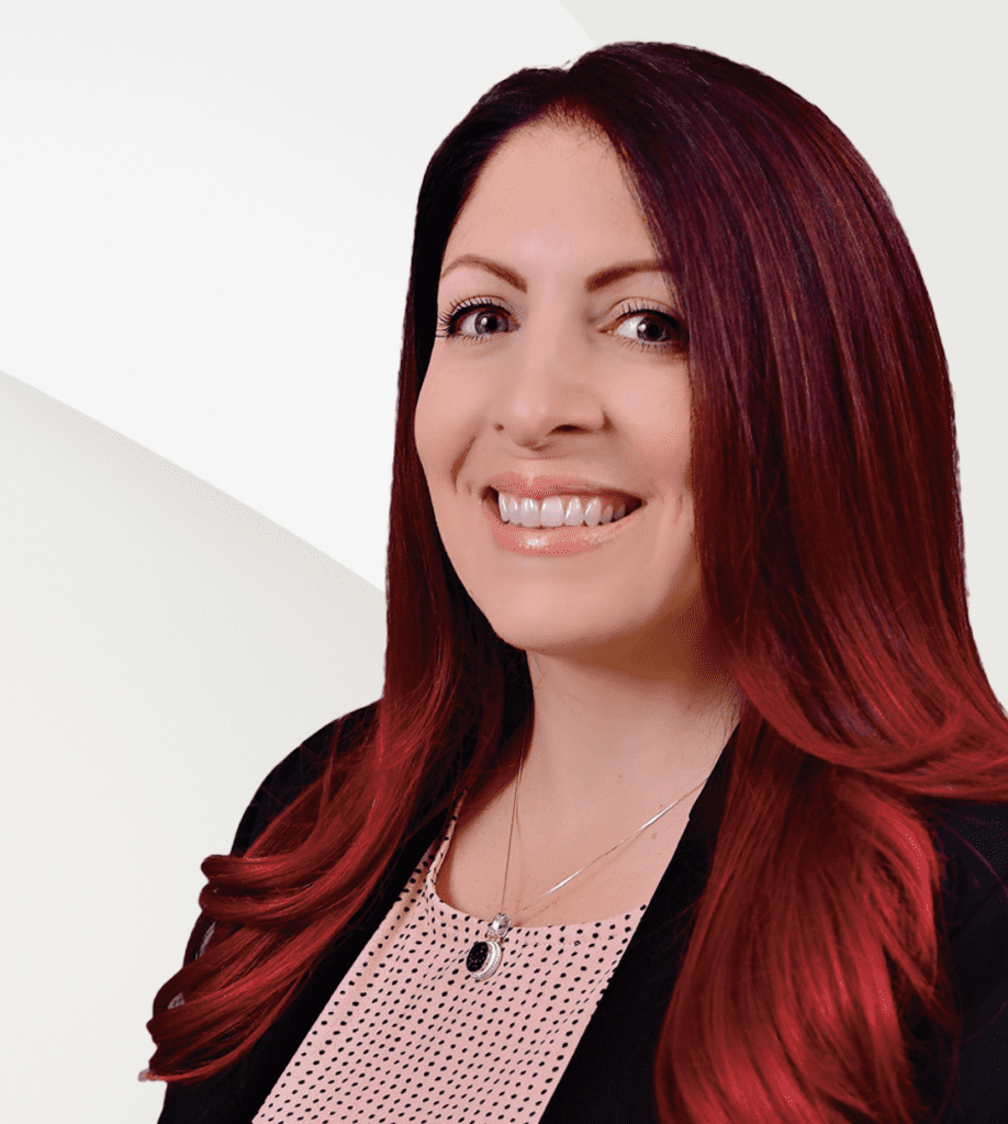 A woman with red hair smiling in front of a white background, representing Engel & Volkers real estate agency.