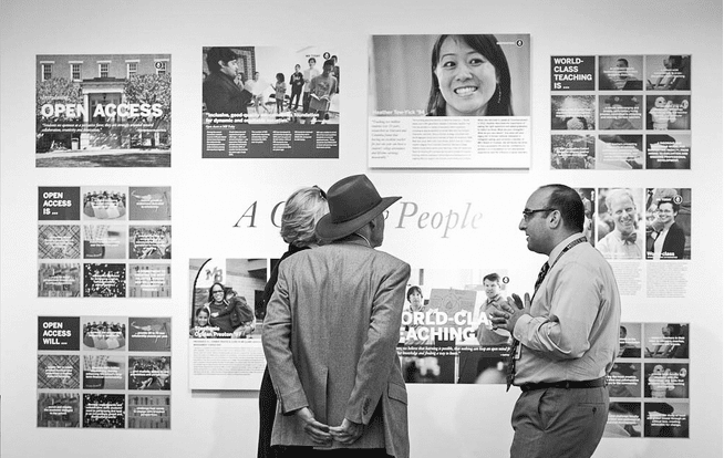 A group of people looking at posters on a wall.