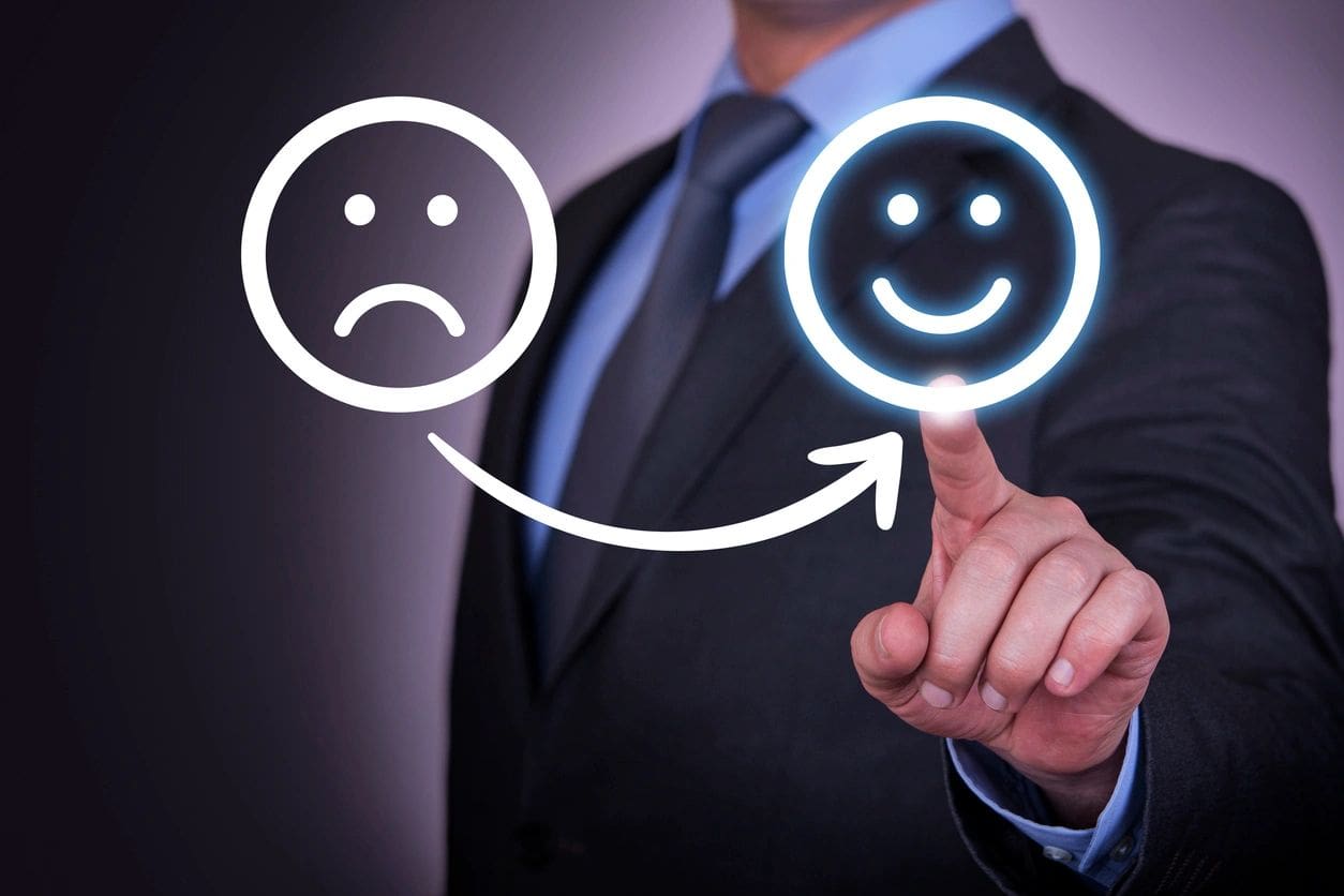 A businessman pointing to a smiley face and a sad face.