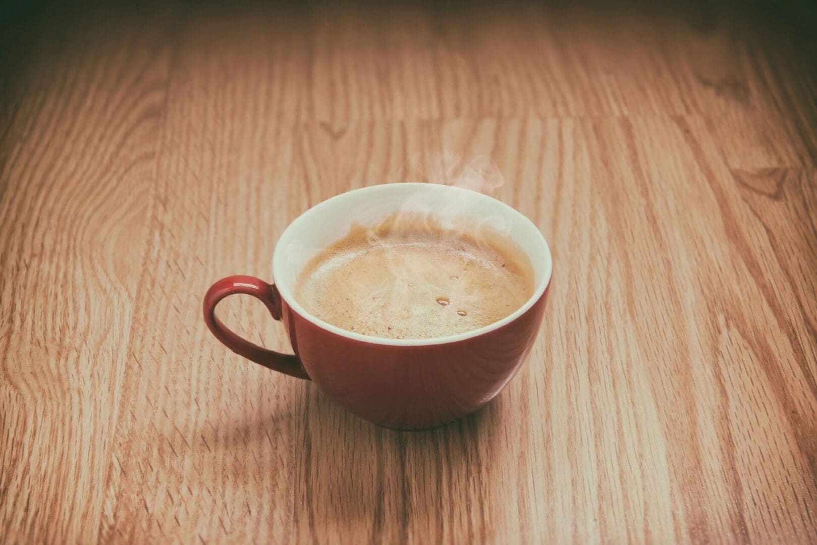 A cup of coffee on a wooden table.