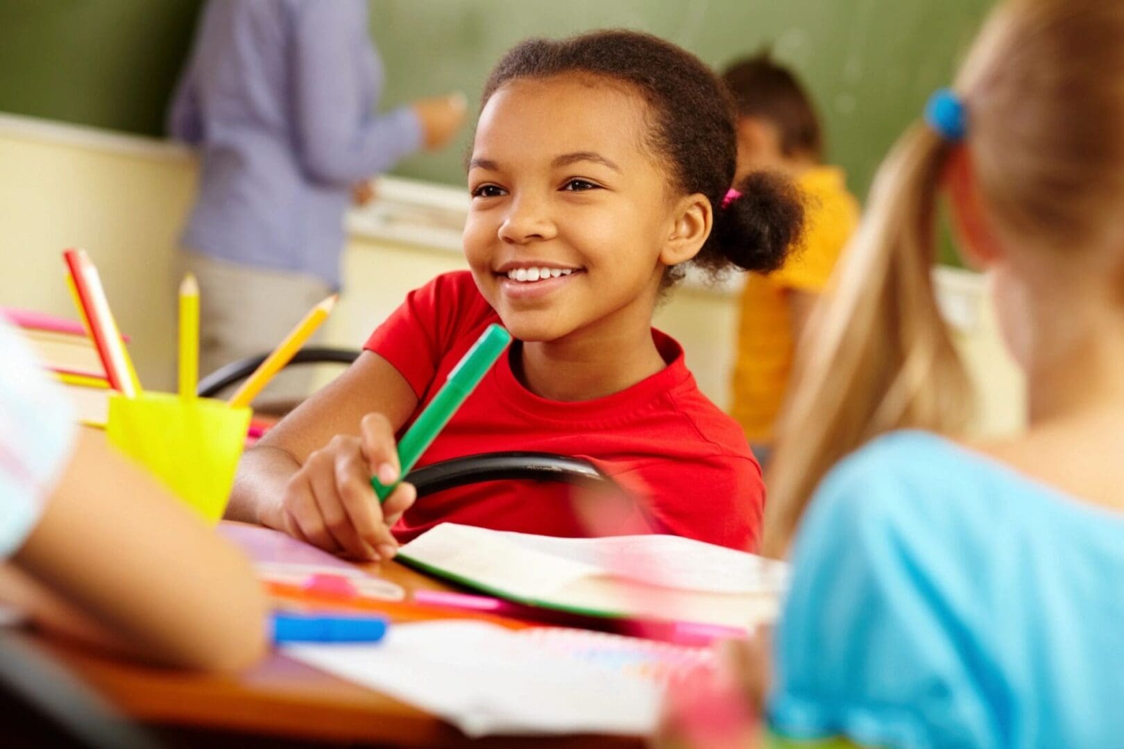 A group of children sitting at a desk in a classroom.