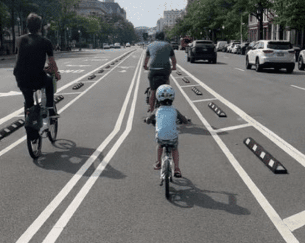 A group of people riding bikes on a city street with bike lanes.