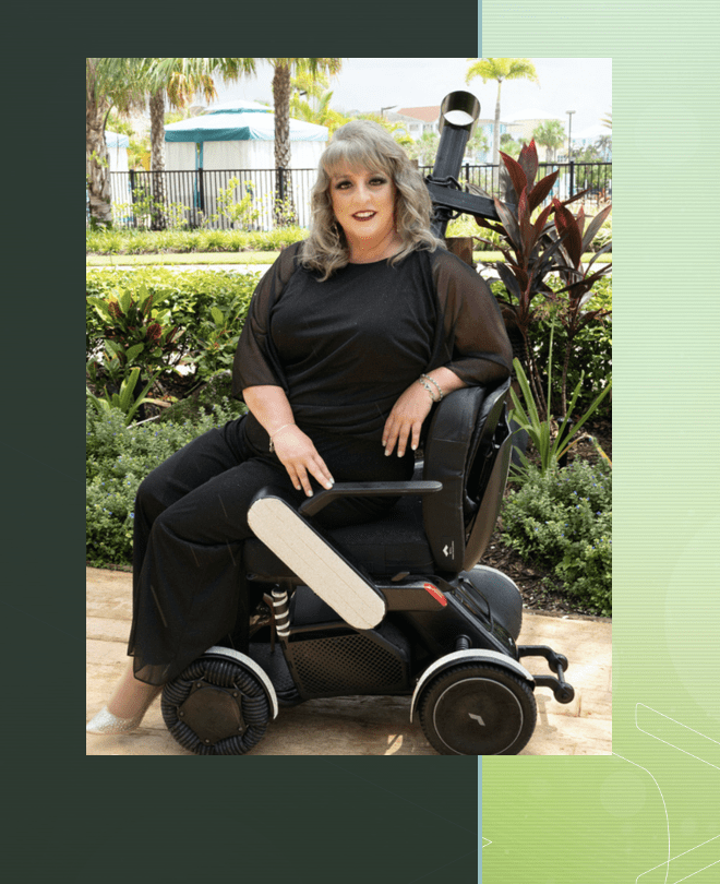 A woman sits in an accessible wheelchair in front of a palm tree.