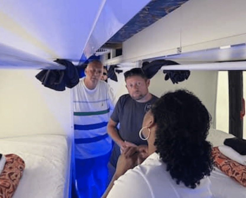 A group of homeless people are standing in a room inside a bus.