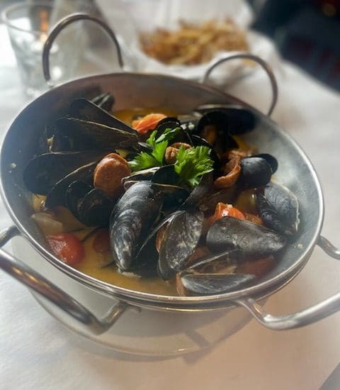 A bowl of mussels and tomatoes on a table, perfect for seafood recipes.