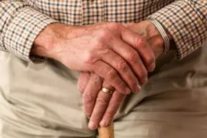 An elderly man is holding a walking stick.
