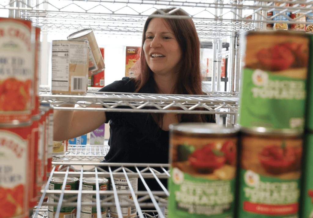 In a food pantry, a woman examines canned food options.