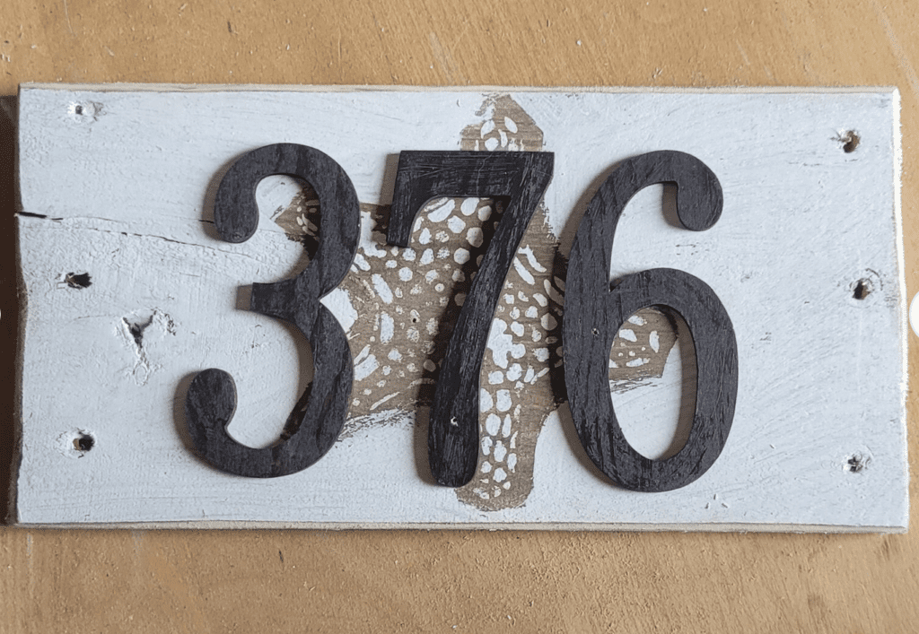 A wooden sign with the number 376 on it, showcasing an artistic touch.