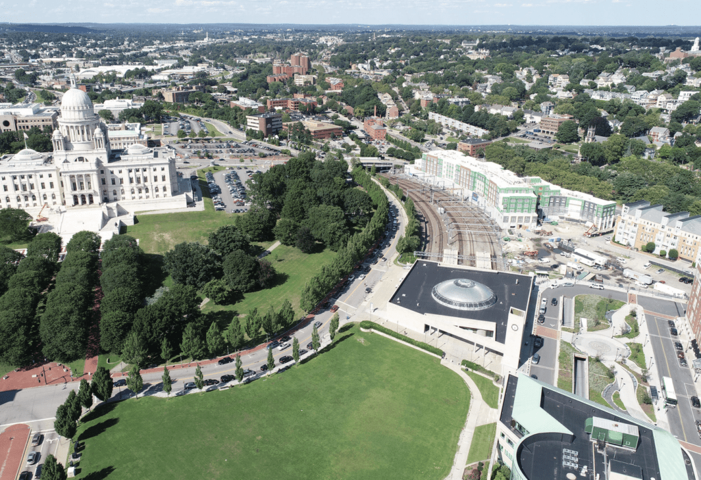 An aerial view of a city with green grass and buildings, including buses in Providence.