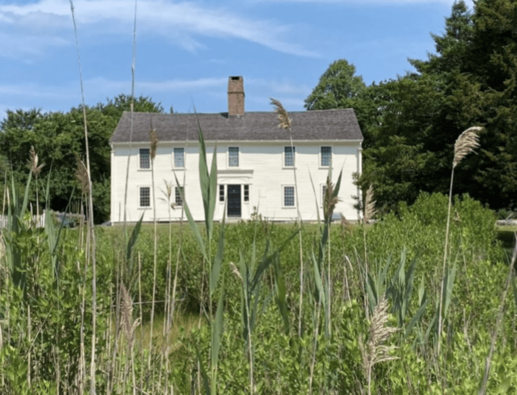 A white house in the middle of tall grass, known as Smith's Castle.