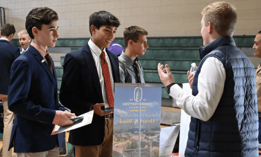 A group of Bishop Hendricken young men talking to each other at a job fair.