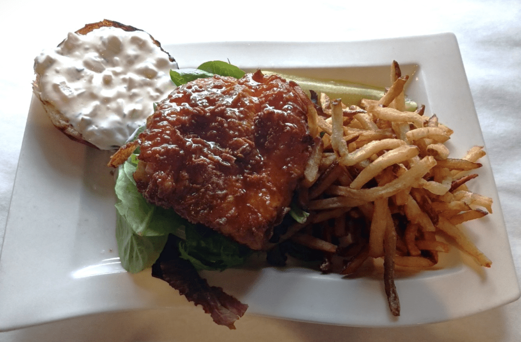 A delicious chicken burger and a side of crispy french fries served on a white plate.