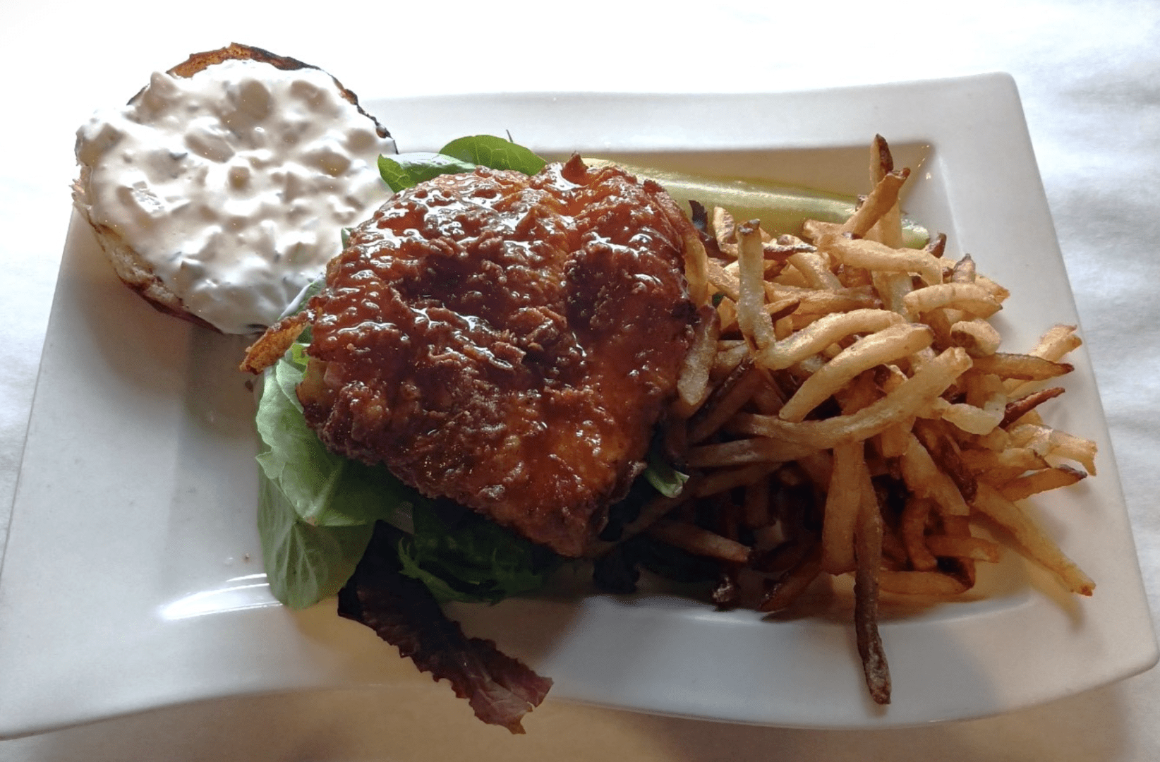 A delicious chicken burger and a side of crispy french fries served on a white plate.