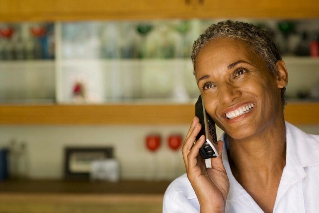 A woman talking on a cell phone in a kitchen.