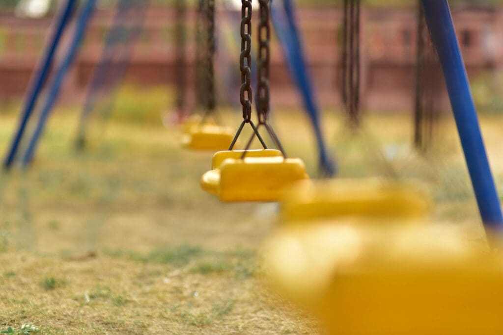 A group of yellow swings in a playground.