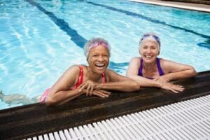 Two older women swimming in a swimming pool.
