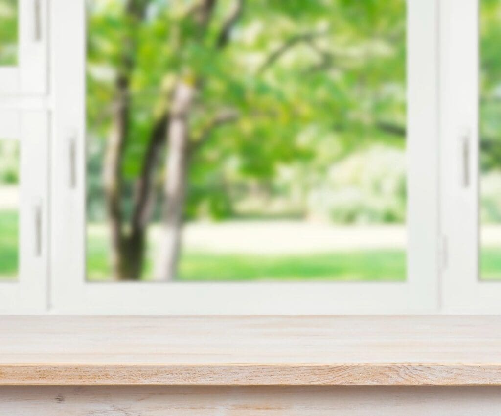 A wooden table in front of a window with a tree in the background.