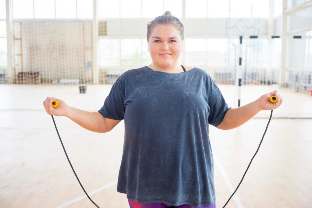 A woman holding a jump rope in a gym.