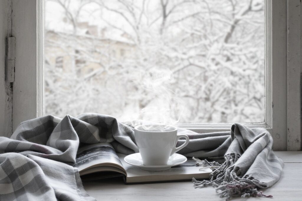 A cup of coffee and a book on a window sill.