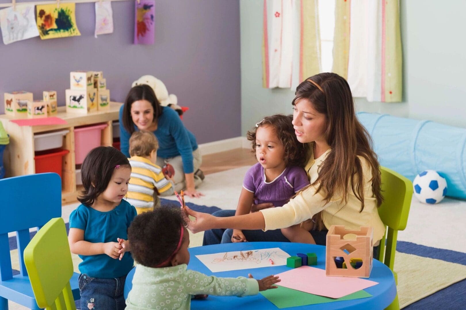 A group of children sitting at a table in a playroom.