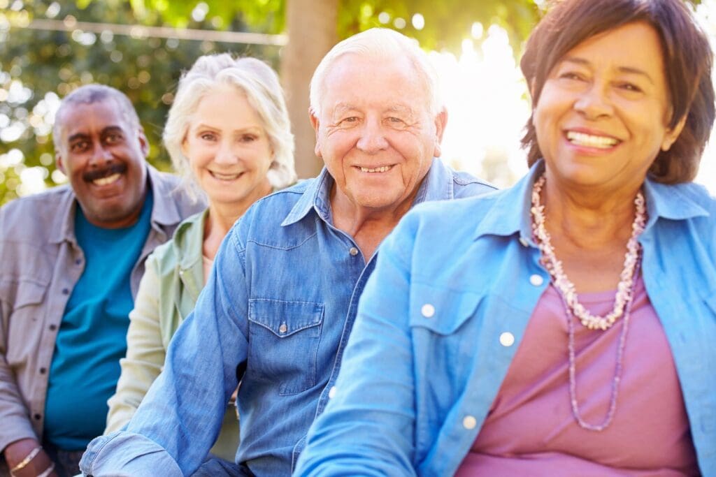 A group of older people sitting on a bench and smiling.