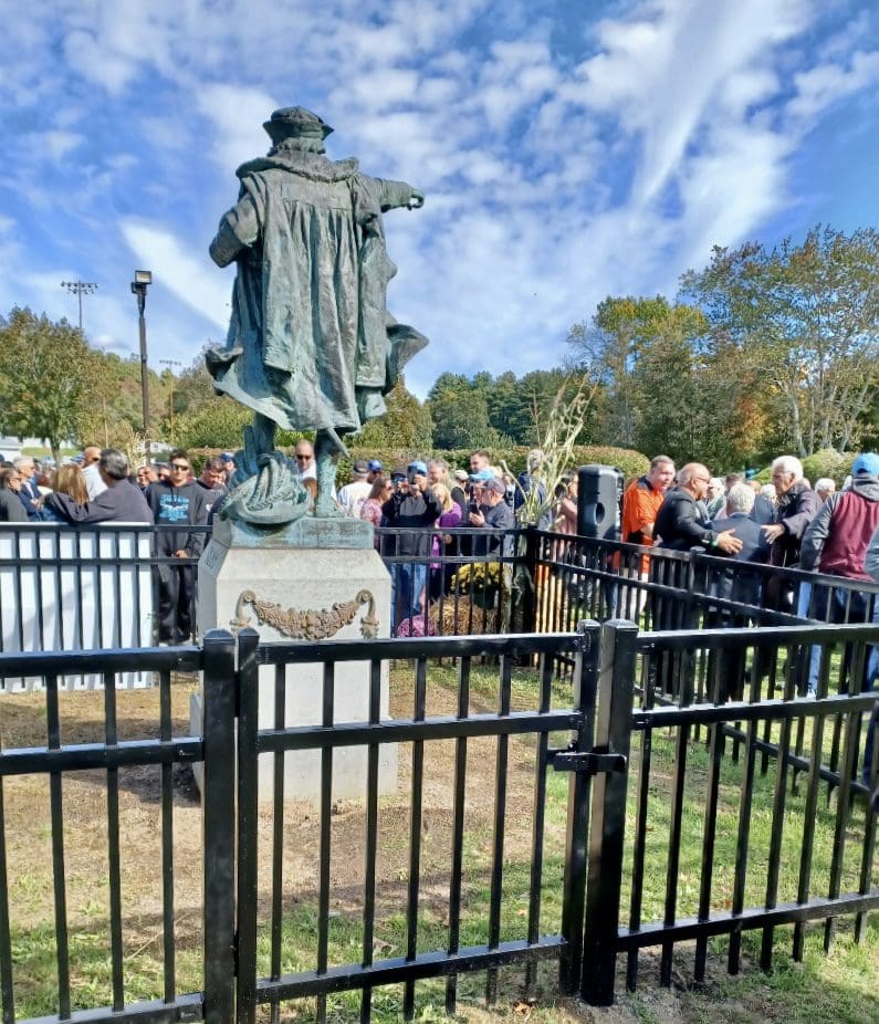 A crowd gathers around a statue of john f kennedy.