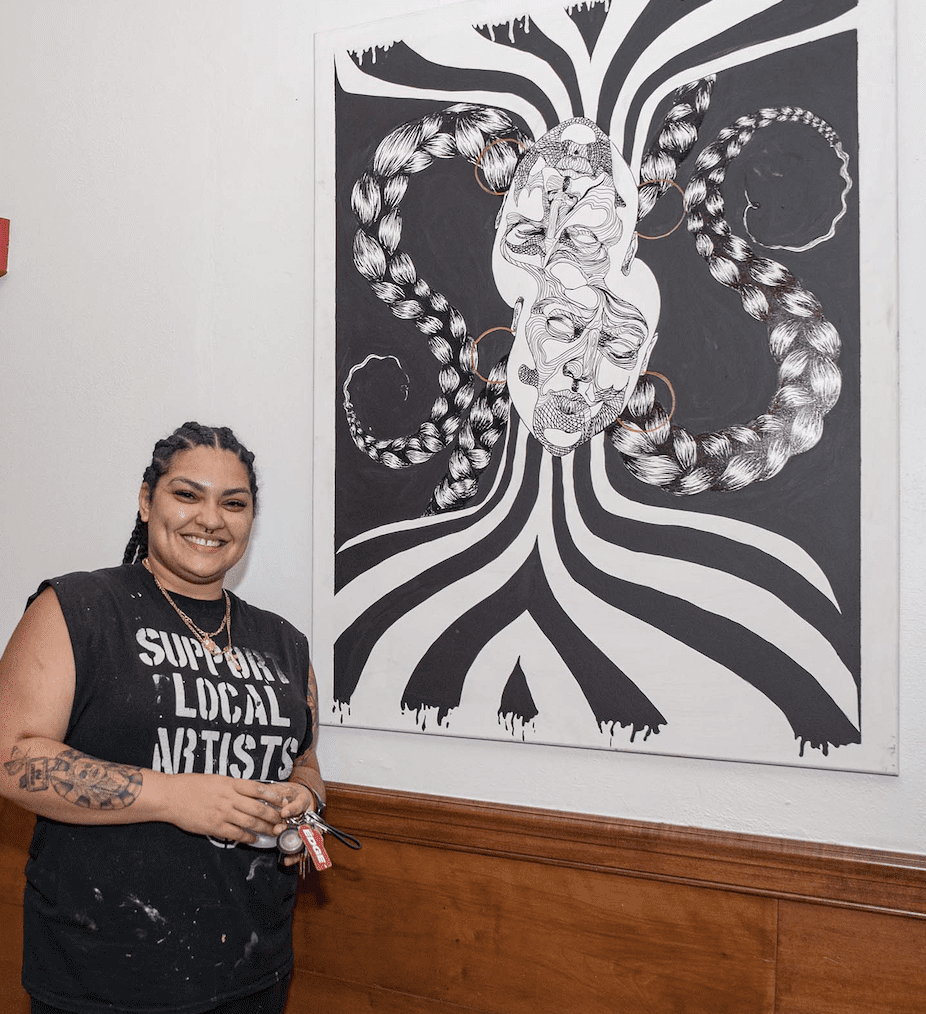 An artist standing in front of a black and white painting.
