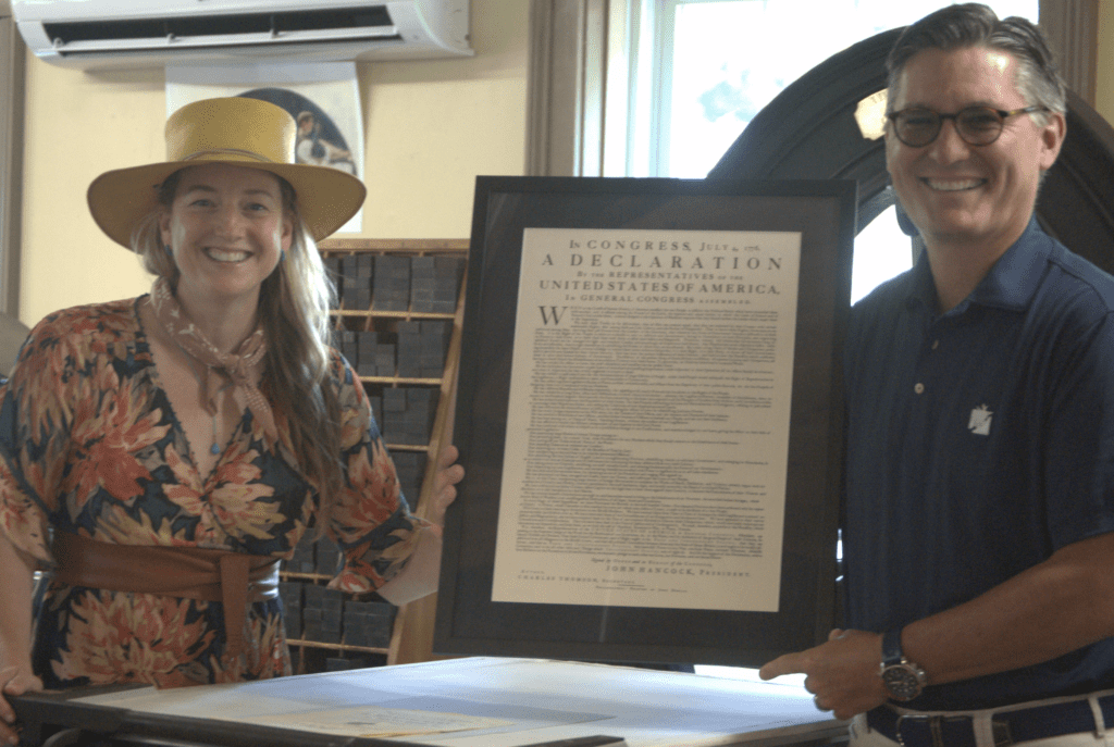 A man and woman standing next to a framed copy of the declaration of independence at BankNewport.