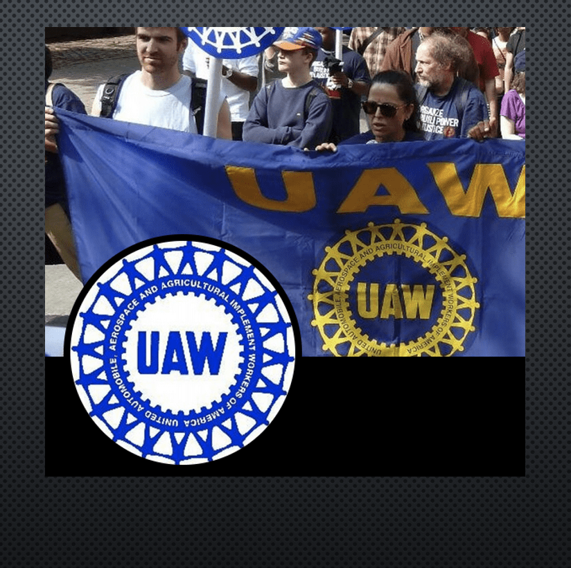 A group of people holding a UAW banner during a strike.