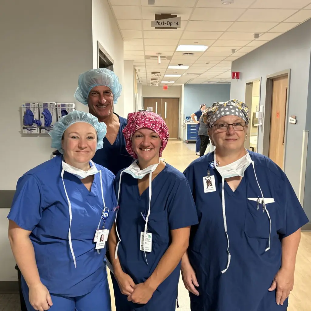 Four nurses in Ortho RI scrubs posing for a photo in a hospital hallway.
