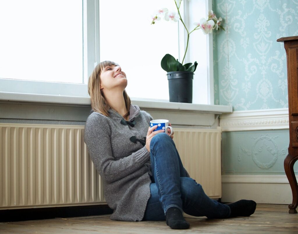 A woman sitting on the floor with a cup of coffee.
