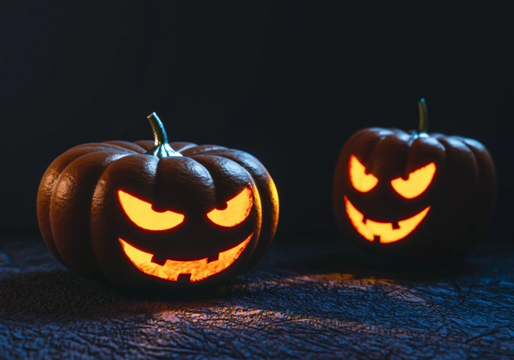 Two carved pumpkins with scary faces on a dark background.