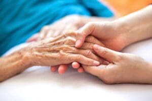 A woman is holding an elderly woman's hand.