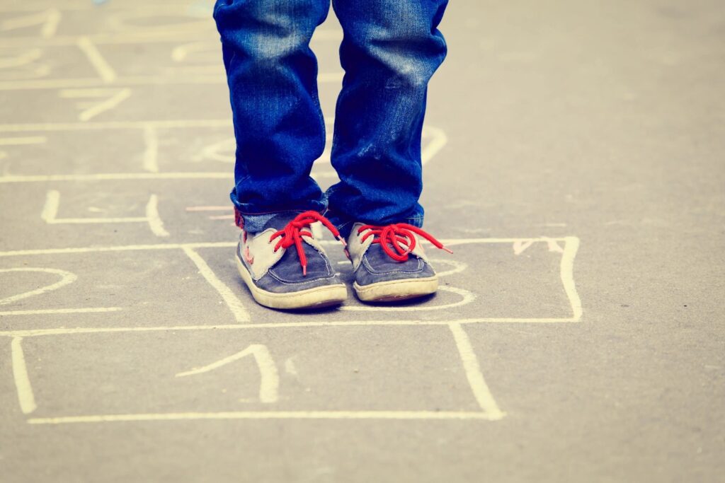 A child's feet standing on a hopscotch board.