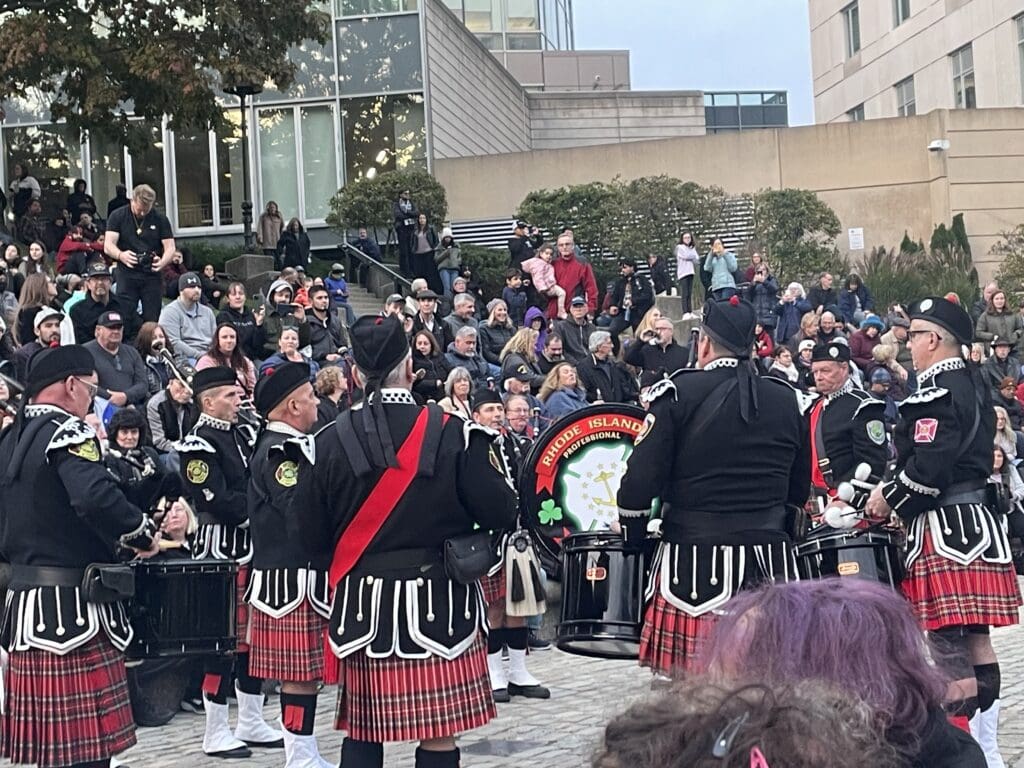 A group of people in kilts are playing in front of a crowd during the Waterfire Salute to Veterans event.