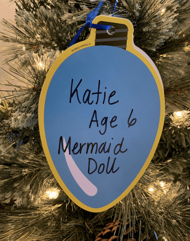 A mermaid doll ornament hanging on a christmas tree for bankRI holiday giving.