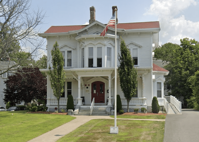 A white victorian house with a flag on the front porch, providing housing for veterans.