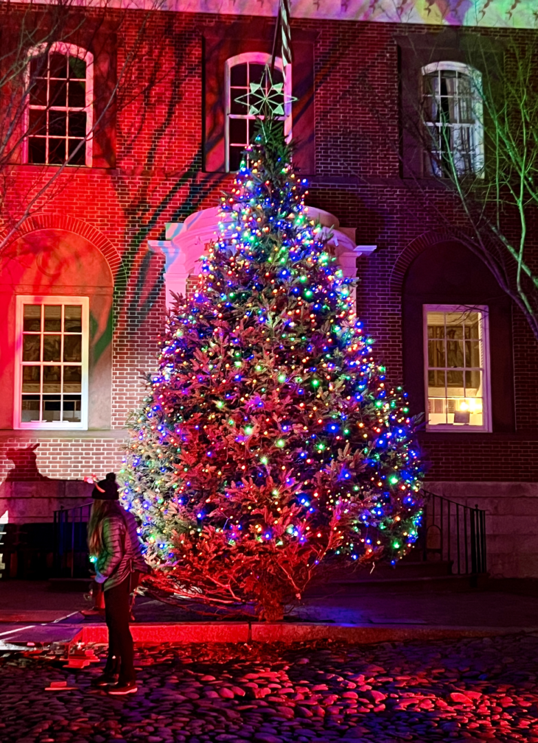 A large Christmas tree lit up in front of a building on Nantucket.