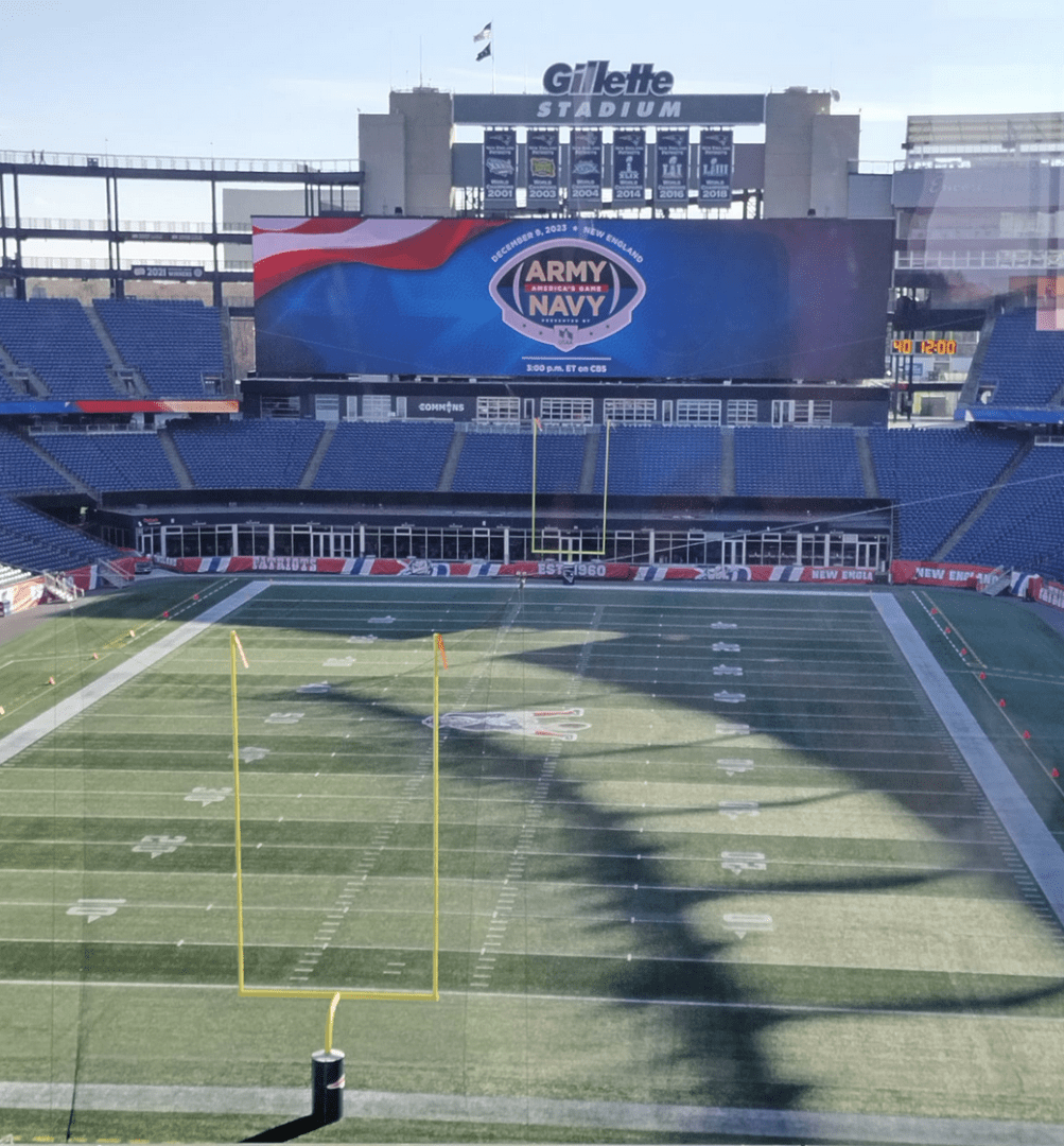 An image of a football field during the Army Navy Game with a large screen.