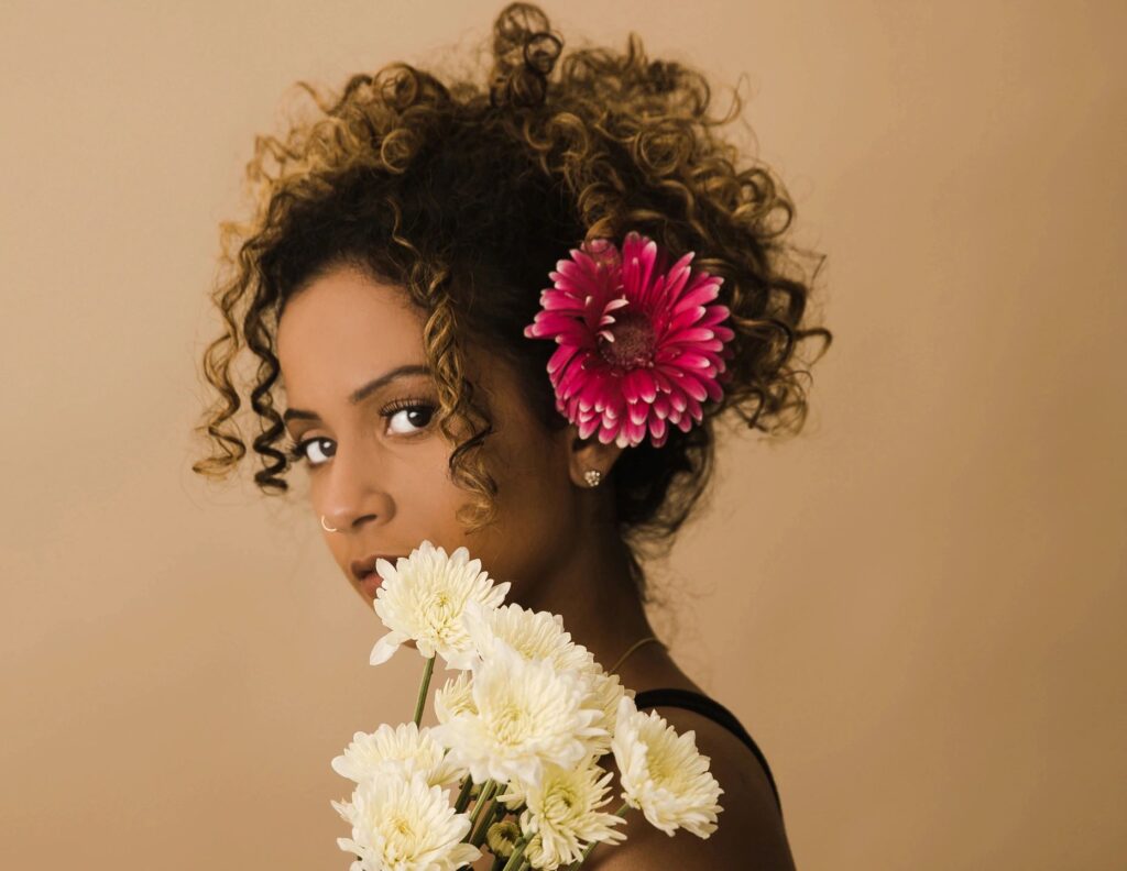 A woman with curly hair holding a bouquet of flowers.