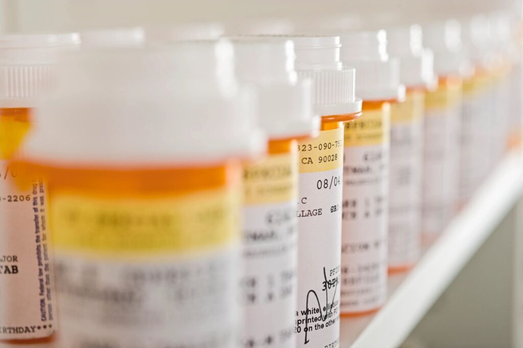 Many prescription bottles are lined up on a shelf.
