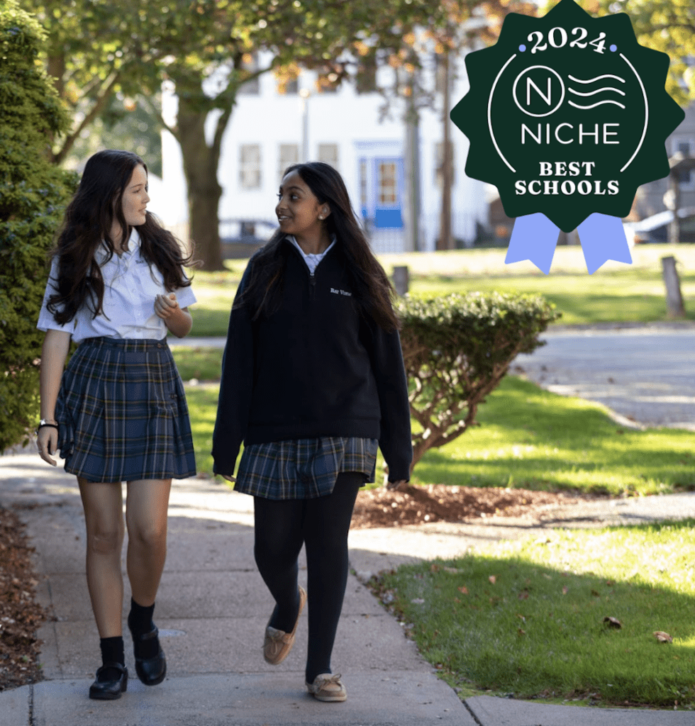 Two girls from Bay View Academy in school uniforms walking down a sidewalk.