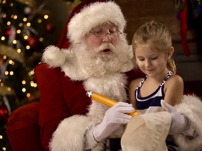 Santa reading a letter to a little girl.