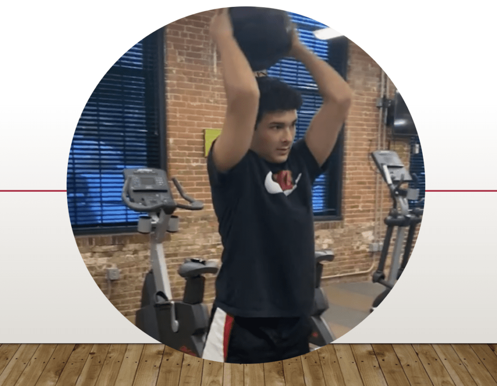 A man performing an exercise of lifting a ball in a gym.