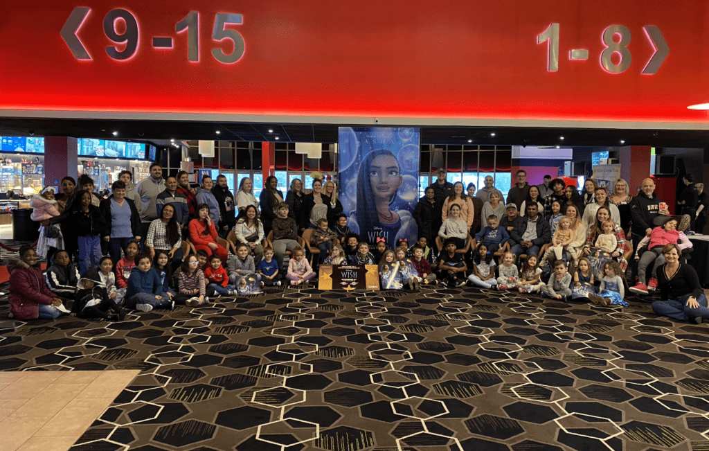 A group of people posing for a photo in a movie theater, capturing "a Wish Come True" moment.