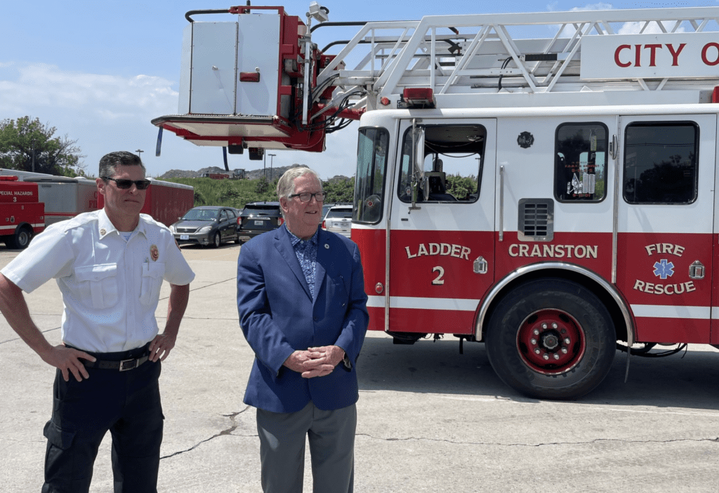 The Cranston fire chief and another man are seen standing in front of a fire truck.