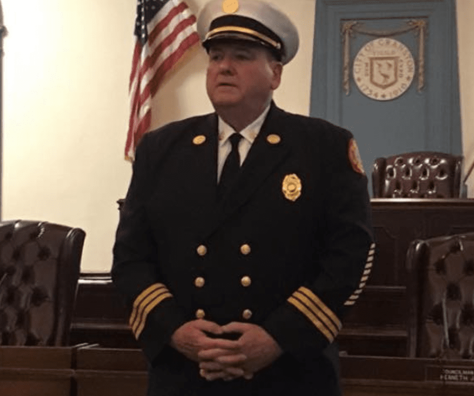 A man in a firefighter uniform standing in a courtroom.